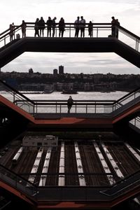 People standing on bridge over river in city