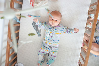 Full length of baby girl lying in crib at home