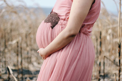 Midsection of woman holding pink while standing outdoors