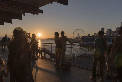 Silhouette people standing by sea against clear sky during sunset