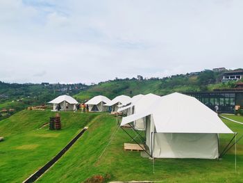 Tent on field by building against sky