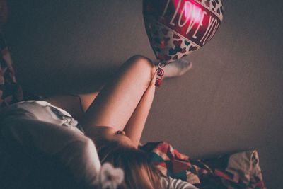 Woman holding balloon with text while relaxing at home