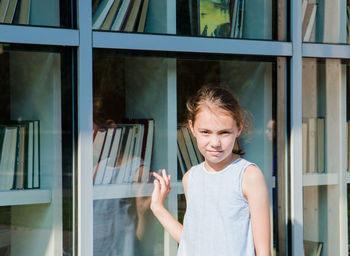 Portrait of girl standing against window