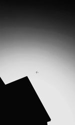 Low angle view of silhouette airplane flying against clear sky