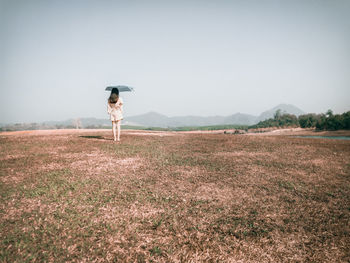 Woman standing on field against clear sky