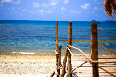 Wooden posts on beach against sky