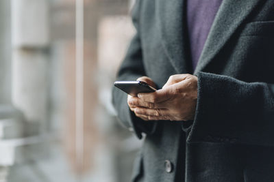 Midsection of man using mobile phone