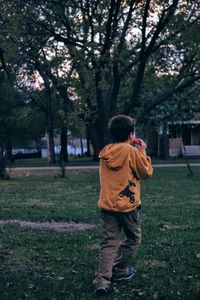 Rear view of boy playing on grass at park