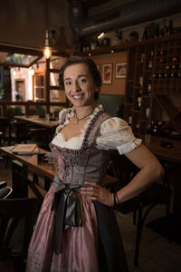 Portrait of smiling young woman standing in restaurant
