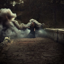 Portrait of woman standing against smoke in forest