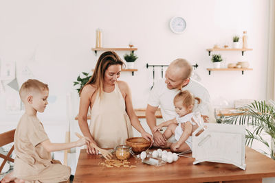 Happy big family of mom dad two kids cooking together and having fun in the kitchen at home