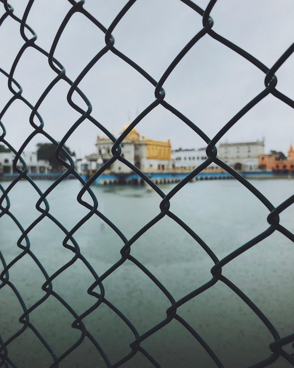 FULL FRAME SHOT OF CHAINLINK FENCE AGAINST SKY SEEN THROUGH METAL RAILING