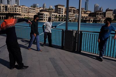 People standing by railing in city against sky