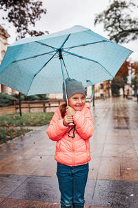 Boy standing on wet umbrella during rainy season