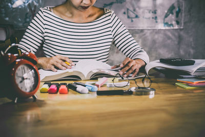 Midsection of woman reading book while sitting on table