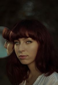 Close-up portrait of young woman with redhead standing outdoors at night