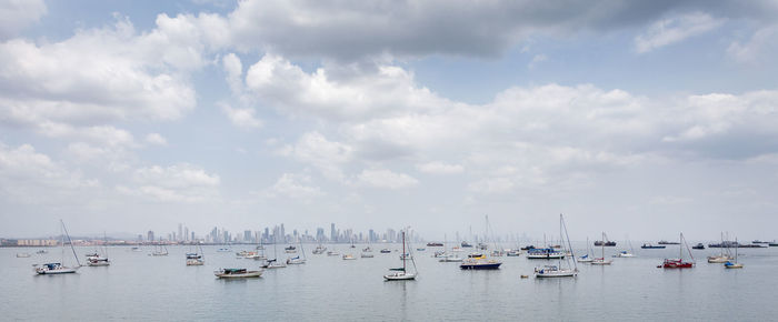 Boats moored in sea against cloudy sky