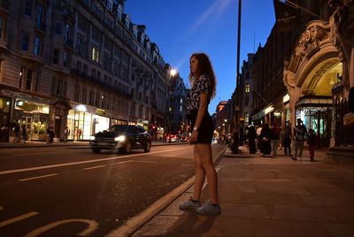 Full length of woman standing on city street at night