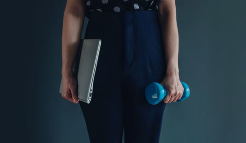 Midsection of woman holding smart phone against black background