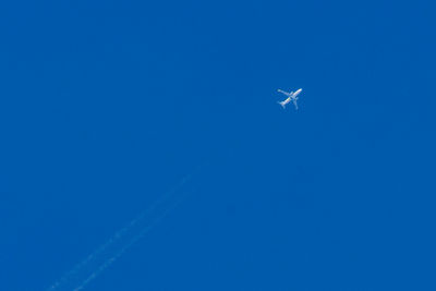 Low angle view of airplane flying against clear blue sky