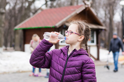 Young woman drinking water in city