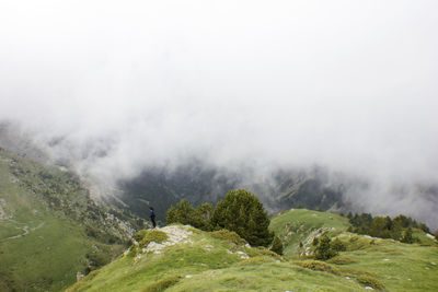 Scenic view of grassy mountains against cloudy sky