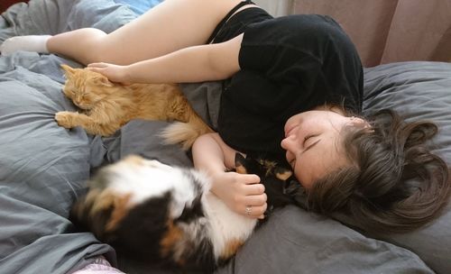 High angle view of woman sleeping with cat on bed at home