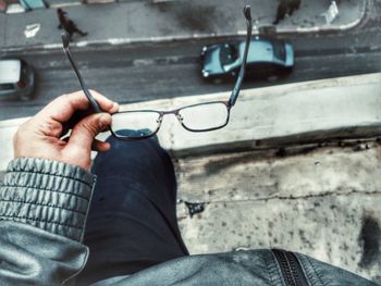 Cropped image of person holding eyeglasses while standing on building terrace