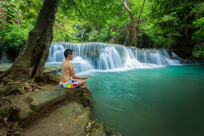 Full length of shirtless boy sitting in water