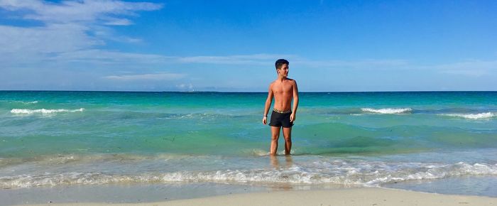 Full length of shirtless man standing on beach