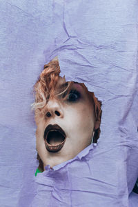 Portrait of shock woman seen through torn paper