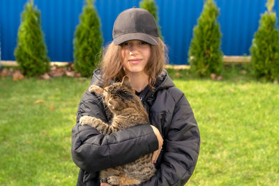 A girl in black holds a cat.