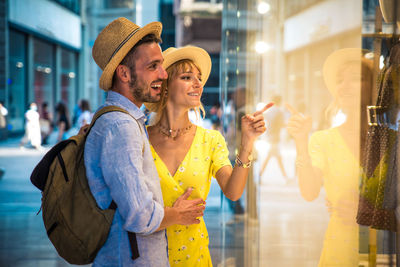 Young woman looking away while standing against store