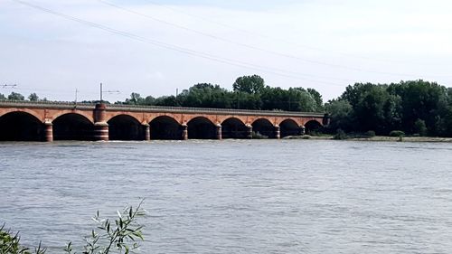 Arch bridge over river against sky