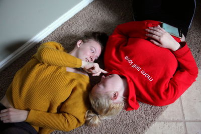 High angle view of young lesbian couple lying on rug at home