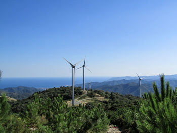 Wind turbines on landscape against sky