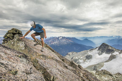 Man climbing rock on mountain against sky