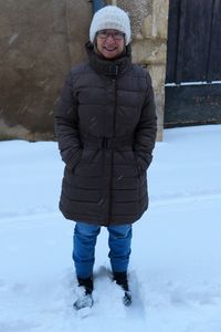 Full length portrait of smiling woman standing on snow
