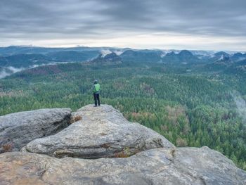 Man stay for a moment for overlooking the misty landscape below view point. trail at edge of cliff