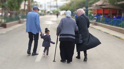 Rear view of two people walking on road