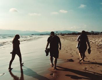 Rear view of people walking on beach