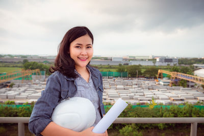 Portrait of smiling young woman standing against sky