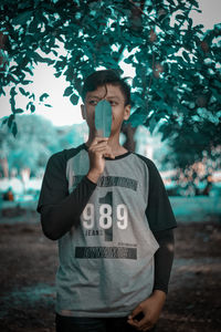 Full length of young man standing against tree