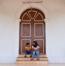 Full length of a man sitting on door of building