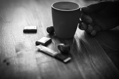 Midsection of person holding coffee cup on table