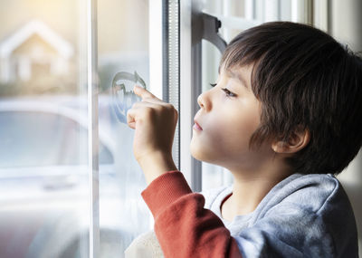 Side view of boy looking through window