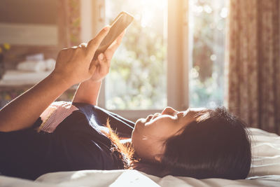 Midsection of woman using mobile phone while relaxing on bed