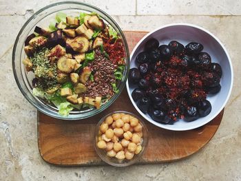 Directly above shot of salad with flax seeds and black olives in bowls on cutting board