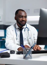 Smiling doctor using computer in clinic