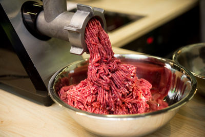 Minced meat comes out of the mincer in a metal bowl, the process of minced meat preparation